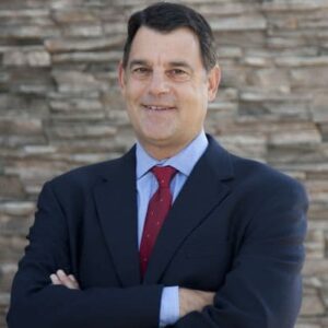 Dan Angress, a white male with dark hair in a dark blue suit, light blue shirt and red tie.