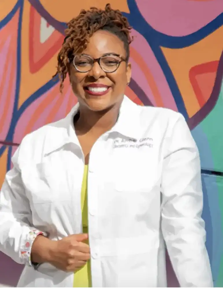 Dr. Amber Glenn, a smiling woman with curly brown hair and glasses.