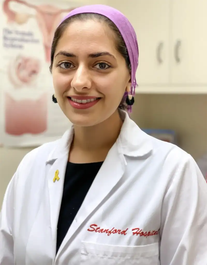 Dr. Atena Asiaii, a smiling woman with dark hair wearing a physician's white coat.