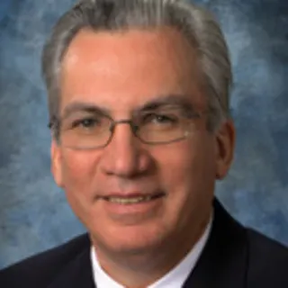 Dr. Rene Charles, a smiling man with grey hair wearing a suit.