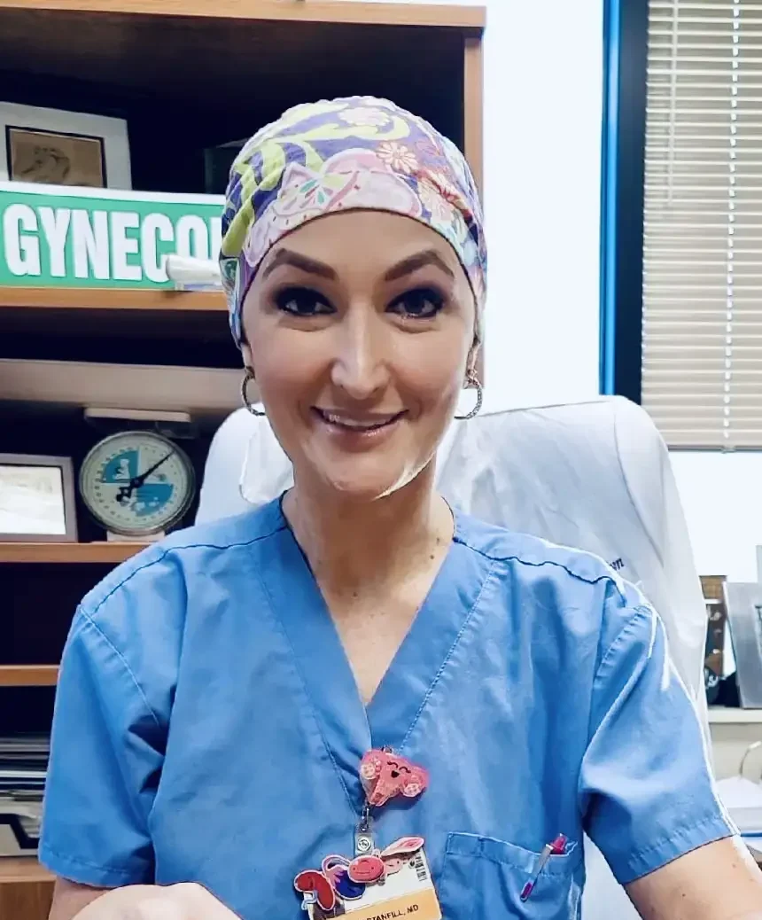 Dr. Tiffany Stanfill sitting at her desk wearing surgery scrubs and cap.